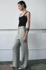 Pantalón de tiro medio con corte flare y pernera ancha. Presenta cintura con trabillas, bolsillos laterales, raya planchada frontal y cierre con cremallera, botón y ganchos metálicos.