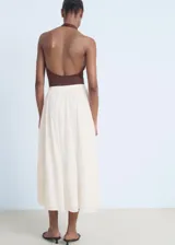 Falda midi de algodón color crudo, con diseño evasé, panel fruncido en la cintura y detalles de puntilla en el ruedo. Cuenta con cierre lateral.