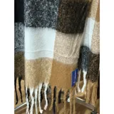 Bufanda rectangular de tejido grueso con diseño de cuadros en tonos azul, naranja, gris y beige, terminada con flecos en los extremos.