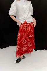 Falda midi de popelina de algodón negra con estampado geométrico de cuadros en tonos blancos, amarillos y rosados, con bolsillos laterales.