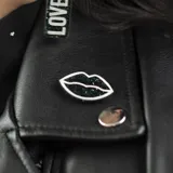 Par de aros con forma de labios negros con glitter y borde plateado.