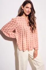 Blusa de corte oversize con estampado de abanicos, cuello redondo con pequeña abertura frontal, cierre de botones y mangas largas con puños elásticos.