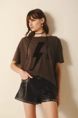 Short de cuero ovino color negro, con remaches metálicos plateados en las presillas, los bolsillos y el ruedo. Presenta un efecto arrugado.