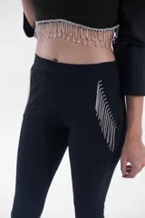 Pantalón negro de corte flare, tiro alto, con detalles de flecos de strass en los bolsillos laterales.