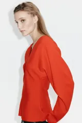 Remera de punto fino en color rojo con escote en V, cintura entallada y mangas dolman largas.