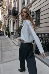 Camisa de popelín color blanco, con cuello solapa, manga larga y bajo abullonado con elástico interior. Cierre frontal con botones.