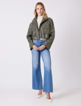 Chaqueta corta de eco cuero color tostado, con cuello alto, cierre frontal con botones a presión y bolsillos de solapa en el pecho. Tiene forro interno a tono.