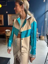 Camisa color beige con detalles en azul metalizado en mangas y pecho, y plateado en cuello y puños.