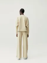 Pantalón recto color beige de tejido Peach-T, suave y elástico, con bolsillos laterales, costura vertical frontal y cordones de ajuste en la cintura.