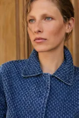 Chaqueta de jean azul con textura de efecto desgastado, cuello clásico y cierre frontal.