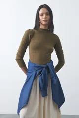 Polera de tejido de punto color celeste, con cuello alto y textura de pequeños puntos en relieve formando una cuadrícula en el frente y las mangas. De corte ajustado y manga larga.
