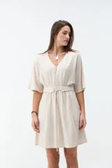 Vestido corto beige con escote en V, mangas cortas amplias y cintura elastizada con lazo ajustable.
