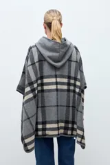 Capa abierta con capucha, diseño a cuadros en tonos grises, negros y beige. Presenta un cierre frontal tipo hebilla de cuero sintético en el cuello y mangas cortas tipo kimono.