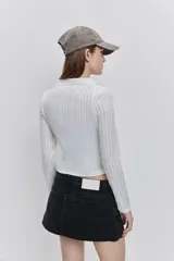 Top de calce al cuerpo color negro, confeccionado en tejido elástico con textura acanalada, con cuello camisero, mangas largas y recorte frontal tipo cut-out.