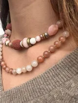 Collar corto de cuentas de piedra luna facetadas en tonos grises, blancos y durazno, con cierre de mosquetón dorado.