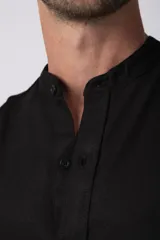 Camisa de manga larga confeccionada en lino, con cuello mao y cierre frontal de botones. Presenta un corte relajado y diseño minimalista.