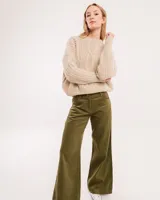 Pantalón de pana color verde oliva, de corte wide leg y largo al tobillo. Tiene cierre delantero con botón, bolsillos laterales y traseros.