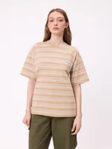 Remera de corte holgado con diseño de rayas horizontales en tonos beige, rosa y verde oliva. Presenta cuello redondo, mangas cortas y un bolsillo frontal pequeño con el logo de la marca.