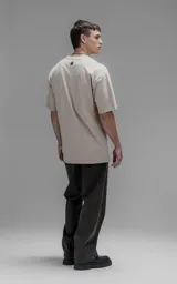 Remera de corte relajado con hombros caídos y silueta amplia, confeccionada en algodón premium. Presenta cuello redondo y mangas cortas, ofreciendo un calce cómodo y versátil.