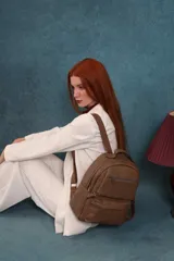 Mochila de cuero sintético color negro con textura granulada. Cuenta con un compartimento principal con cierre, un bolsillo frontal con cierre, correas ajustables y asa superior.