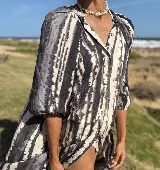 Vestido tipo camisero con estampado tie dye en tonos blanco y negro, cuello a la base, cierre frontal con botones y mangas al codo con terminación elástica.