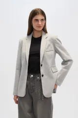 Blazer gris con cuello solapa, bolsillos frontales y cierre con dos botones.
