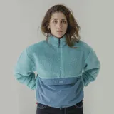 Buzo de sherpa color celeste con corte a la altura del pecho y bolsillo de nylon azul con logo estampado.