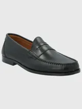 Zapato tipo mocasín de cuero negro con diseño clásico, costuras visibles en la puntera y detalle de antifaz en el empeine.