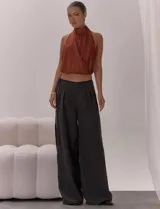Top de escote halter con cuello alto, diseño frontal cruzado con pliegues y espalda descubierta con lazo regulable. Presenta una terminación elasticada en la cintura y está confeccionado en una tela liviana con caída fluida.