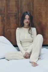 Pantalón negro de tejido de punto, tiro alto, con cintura elástica y detalle de tres botones frontales. Corte de pierna recta y ancho.