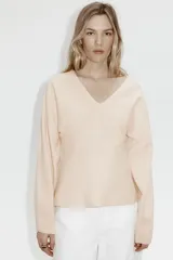Remera de punto fino suave color beige con escote en V, modelo de cintura entallada con mangas dolman largas.