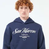 Buzo azul marino con capucha y cordones ajustables. Estampado frontal con el texto "San Marcos California State University" en color blanco.