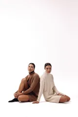 Vestido corto de tejido de punto color marrón, con cuello alto y mangas largas. Presenta un diseño de silueta relajada y terminaciones acanaladas en puños y ruedo.