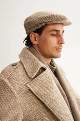 Boina con visera de lana fina uruguaya natural, sin teñir, con diseño de tejido texturizado en tonos beige y marrón.