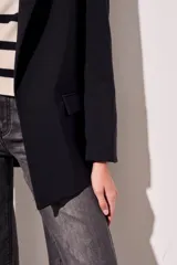 Blazer negro de corte clásico con solapas y mangas largas con puños con rayas verticales.