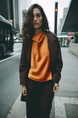 Abrigo largo de Zara confeccionado en hilatura con lana, de color marrón oscuro. Cuenta con cuello solapa, manga larga, bolsillos de vivo en el delantero y cierre frontal con dos botones.