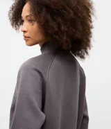 Buzo de algodón con felpa, de corte estructurado y diseño cropped. Presenta cuello alto con medio cierre frontal, mangas largas con puños elásticos y ruedo con elástico ancho.