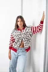 Saco de punto con diseño combinado, presentando un estampado de animal print en el frente y mangas a rayas horizontales en rojo y beige. Posee cuello redondo, cierre frontal con botones y terminaciones en tejido acanalado de color rojo.