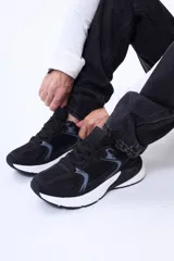 Championes urbanos de diseño clásico, confeccionados en una combinación de cuero sintético y tejido de malla. Presentan una base blanca con detalles en gris y acentos en azul oscuro, con suela de goma robusta y cierre de cordones.