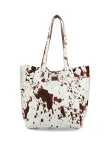 Cartera shopper confeccionada en cuero con pelo con estampado animal print tipo vaca en tonos blancos y marrones, con doble asa de hombro y bolsillo interior con cierre.