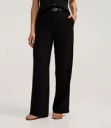 Pantalón de vestir negro de sastrería, corte wide leg y tiro alto. Presenta cierre frontal y trabillas en la cintura, e incluye un cinturón fino de poliuretano.