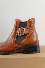 Botín negro de charol con punta cuadrada y hebilla metálica decorativa.