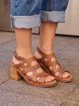 Sandalias de cuero color marrón, con taco ancho, diseño de tiras cruzadas y hebilla metálica de ajuste en el tobillo.