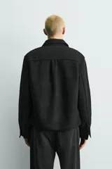 Sobrecamisa de corte relajado confeccionada en tejido de estructura irregular con lana. Presenta cuello solapa, cierre frontal con botones, mangas largas con puños abotonados y bolsillos frontales con solapa en el pecho.
