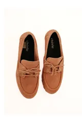 Mocasines de gamuza color tostado con lazo frontal decorativo y detalle de pasacintas laterales. Poseen suela flexible antideslizante.