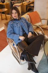 Saco de punto color azul, con bordados florales artesanales en la zona de los hombros y botones forrados en crochet. Presenta un diseño clásico con cuello redondo y mangas largas con terminaciones caladas.