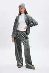 Pantalón de corte ancho confeccionado en tela de plush con acabado satinado. Presenta cintura elástica con cordón de ajuste y bolsillos laterales.