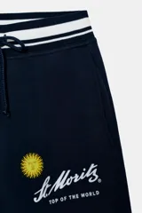 Pantalón de felpa azul marino con tiro alto, cintura elástica con cordón ajustable y diseño de pierna ancha. Presenta un estampado frontal con el logo de St. Moritz y un sol amarillo.