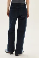 Jean recto de tiro medio, color azul oscuro, con franja lateral de tela gris más clara. Presenta un efecto de textura sutil en la tela principal.