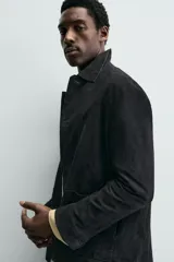 Sobrecamisa de ante color negro, con corte relaxed fit, cuello solapa, manga larga con puño abotonado, bolsillos de plastrón en la cadera y cierre frontal con botones.